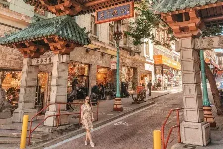 一名女子站在贝博体彩app唐人街入口处的一扇华丽的门前。.